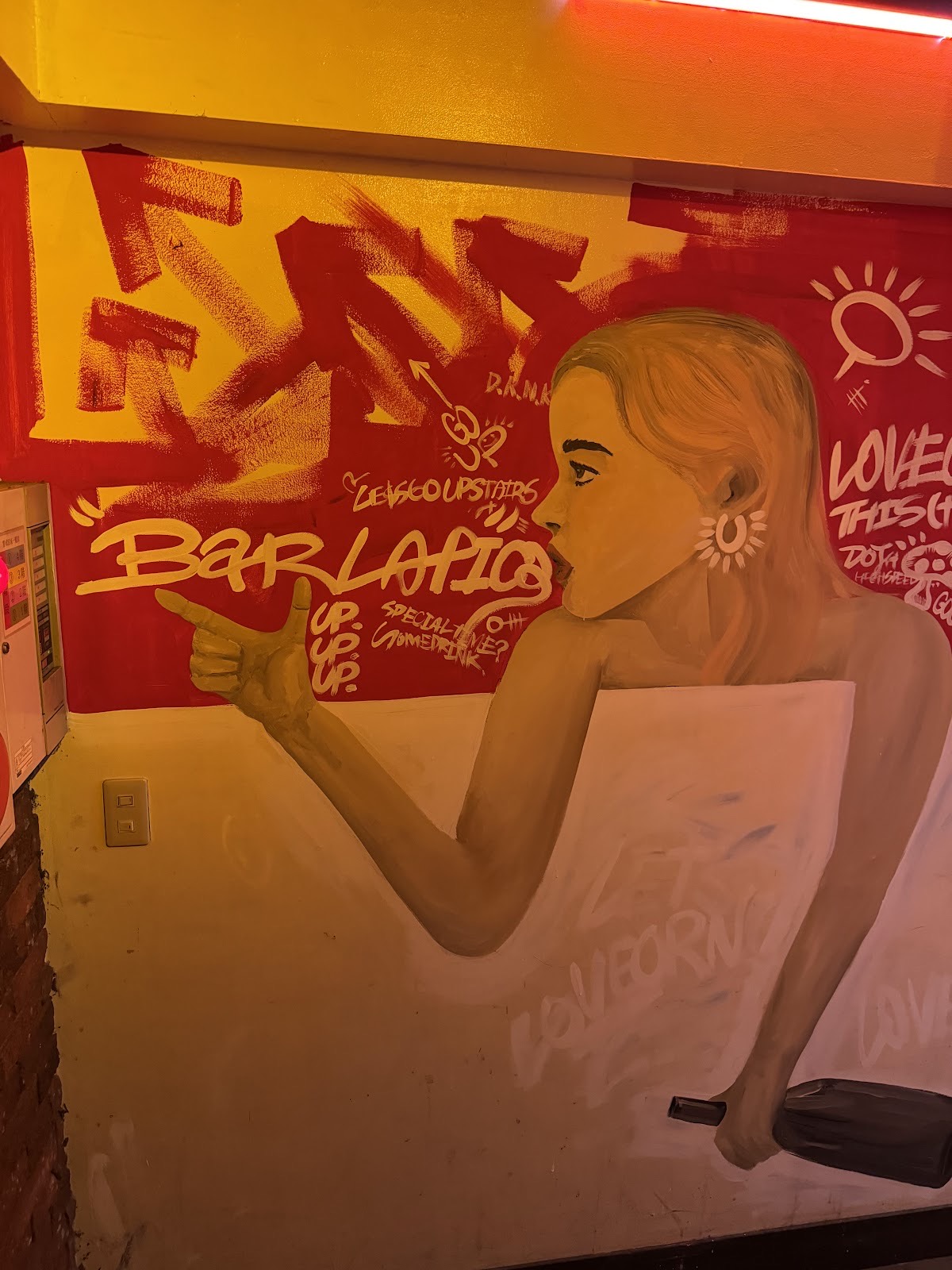 赤と黄色の壁画。横顔の女性が筆記体の「Bar LaFica」の文字を指さし、まわりに「LET'S GO UPSTAIRS」「UP. UP. UP.」の手書き文字。